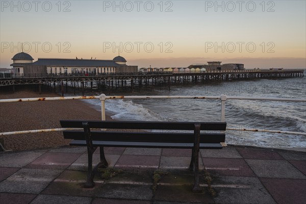 Hastings, East Sussex, England, UK, May 11, 2022: Evening mood on the beach, with a bench overlooking the the pier