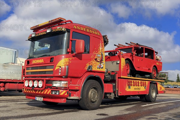 Scania flatbed tow truck of Hinaus Andersson Oy carrying a vintage fire truck. Salo, Finland. August 6, 2015