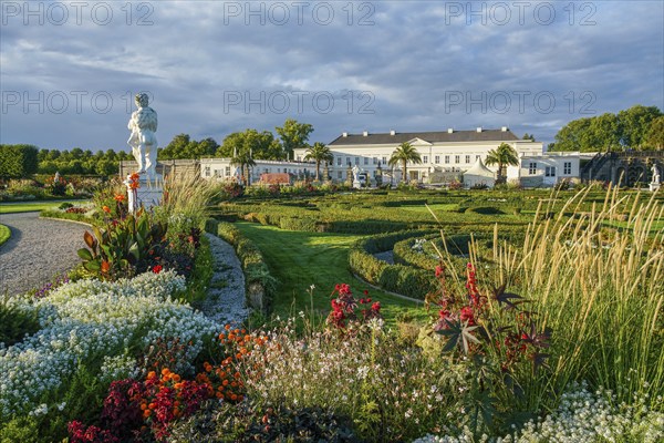 Fantastic Herrenhausen gardens of Hannover with statue and luxury colorful flowerbeds with shiny sunset. Idea of gardens by Princess Sophia of Hanover, Garden Path and cereals and many flowers. Palace in distance. in 1666