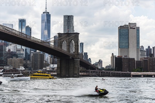 New York City, USA, June 24, 2018: Cityscape of Downtown of Manhattan and Brooklyn Bridge with jet ski and tour boats navigating on East River, North America