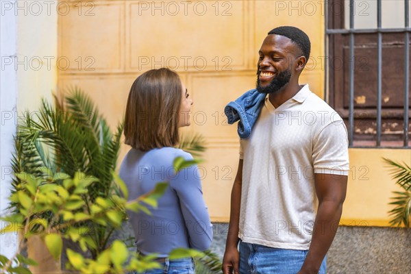 Multi-ethnic african and caucasian couple talking relaxed and smiling in the street