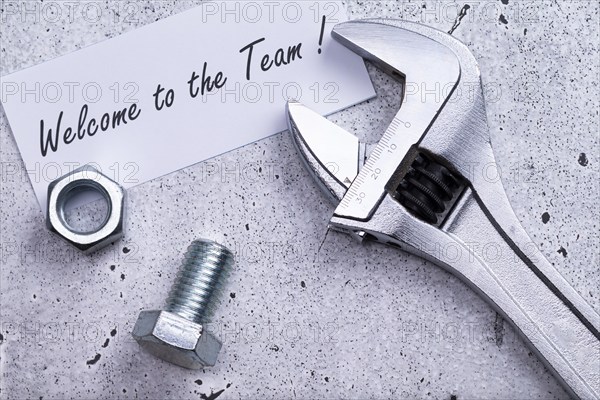 The photo shows a label with the inscription 'welcome to our team' with a spanner and screw on a grey background