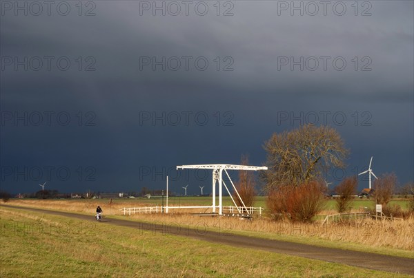 Cyclist tries to stay ahead of a heavy shower on a bicycle path in the Dutch province Friesland