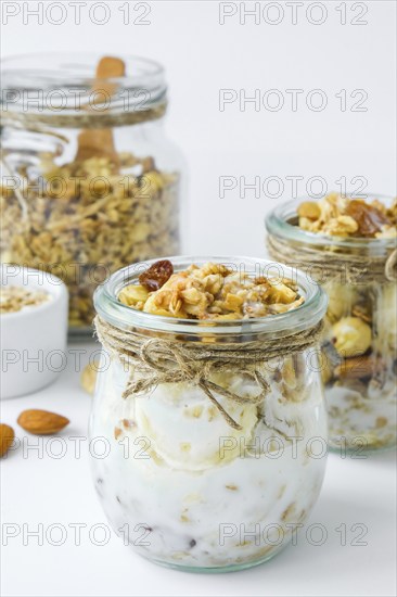 Healthy breakfast. Oatmeal Granola with greek yogurt and nuts banana muesli in jars on light background. Vegan, vegetarian and weight loss diet concept. Detox menu. Healthy eating food