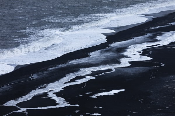 Foamy white waves and icy surfaces on the black pebble beach Skogarsandur, near Dyrholaey, Sudurland, Iceland, Europe