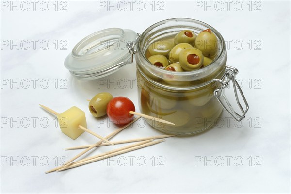 Green olives in glass and on toothpicks with tomato and cheese cubes