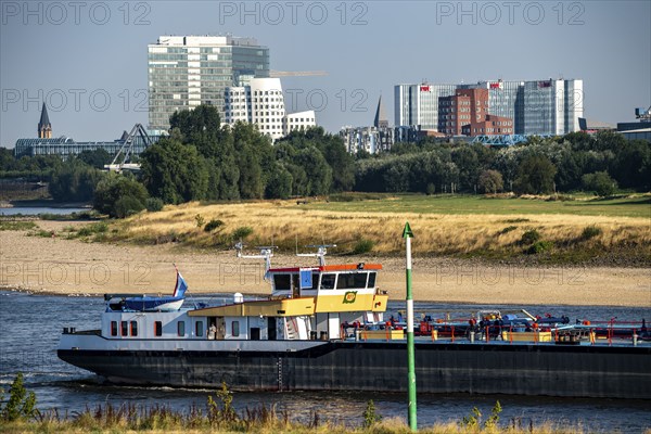 Rhine at Düsseldorf, extremely low water, Rhine level at 47 cm, falling, barge in front of the skyline with the Gehry houses, sandbanks, freighters are only allowed to sail with very reduced cargo and very slowly, North Rhine-Westphalia, Germany, Europe