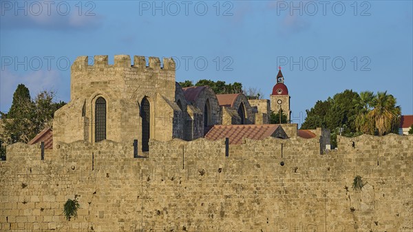 City wall, St Mary's Church, Clock tower, Historic stone walls of a medieval fortress with towers and vegetation in the background against a blue sky, Rhodes Old Town, Rhodes Town, Rhodes, Dodecanese, Greek Islands, Greece, Europe