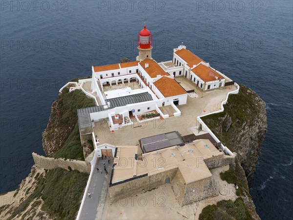 A red lighthouse on a rock above the ocean with several white buildings giving a calm feeling, aerial view, lighthouse, Cabo de São Vicente, Cape St Vincent, Cape St Vincent, Sagres, Portugal, Europe