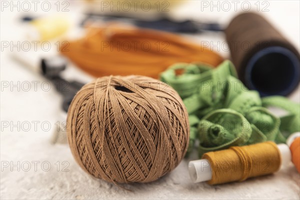 Sewing accessories: scissors, thread, thimbles, braid on gray concrete background. Side view, close up, selective focus