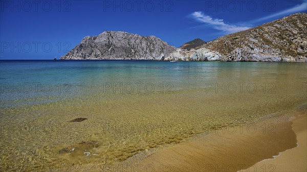 Beach with clear water and a golden sandy beach surrounded by rocks and a blue sky, Psili Ammos Srand, Patmos, Dodecanese, Greek Islands, Greece, Europe