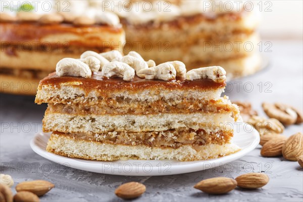 Piece of homemade cake with caramel cream and nuts on a gray concrete background. side view, close up, selective focus