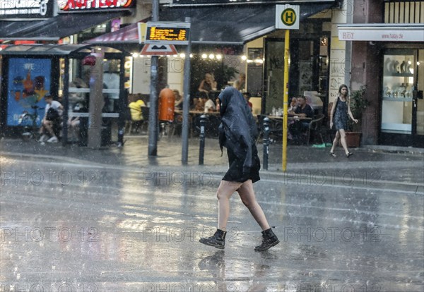 People run across Potsdamer Strasse in heavy rain. After weeks of heat, the first heavy rain brought cooling, Berlin, 15.08.2022