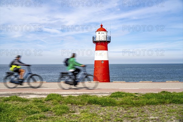 North Sea dyke near Westkapelle, Westkapelle Laag lighthouse, cyclists on the Zeeuwse Wind Route cycle path, province of Zeeland, Walcheren peninsula, Netherlands