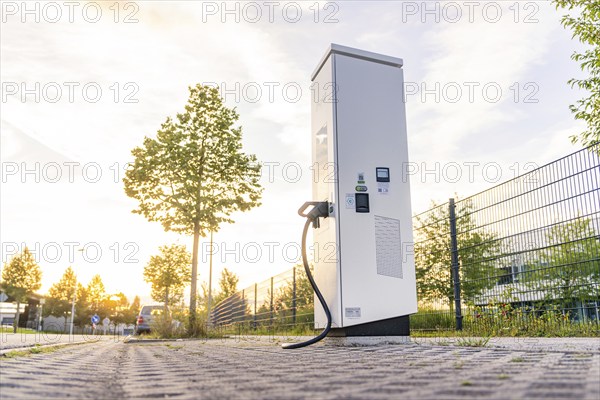 An electric charging station on a cobblestone street at sunset, surrounded by trees and urban surroundings, Calw, Black Forest, Germany, Europe