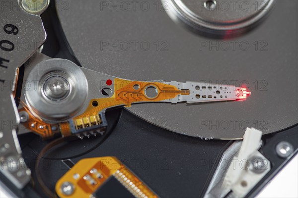 Computer hard drive, opened, read/write head on the storage disc. Symbol image