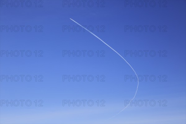 Contrail of airplane outlined in clear blue sky over Suffolk, England, UK