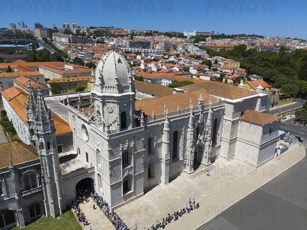 Gothic church with impressive tower and detailed façade in front of an urban landscape with orange-coloured roofs, aerial view, Hieronymus Monastery, Mosteiro dos Jerónimos, Hieronymite Monastery, World Heritage Site, Monastery Church of Santa Maria, Belém, Belem, Bethlehem, Lisbon, Lisboa, Portugal, Europe