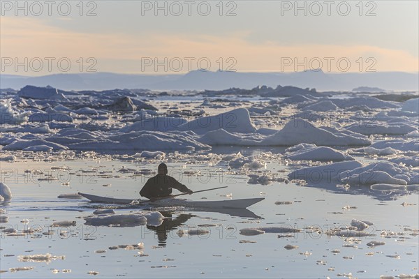 Inuit paddling a kayak between icebergs, man, sunny, summer, Ilulissat, Ilulissat Icefjord, Disko Bay, West Greenland, Greenland, North America