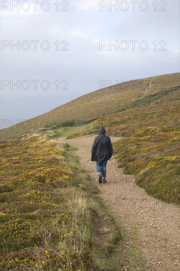 Woman wearing kagoule walking along the South West coast path at St Agnes head, Cornwall, England, United Kingdom, Europe