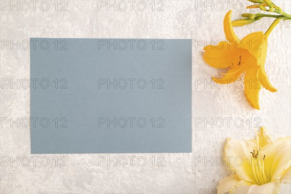 Blue paper business card mockup with orange day-lily flower on gray concrete background. Blank, top view, copy space, still life. spring concept