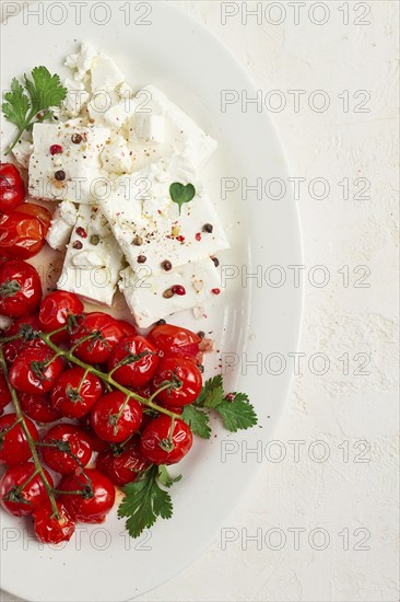 Baked cherry tomatoes, with cheese, and spices, on a white plate, homemade, no people