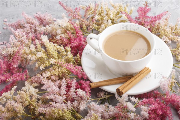 Pink and red astilbe flowers and a cup of coffee on a gray concrete background. Morninig, spring, fashion composition. side view, close up