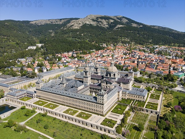 Historic monastery and neighbouring town, surrounded by green landscape and mountains, seen from the air, aerial view, Real Sitio de San Lorenzo de El Escorial, Royal Seat of Saint Lawrence of El Escorial, palace and monastery complex, San Lorenzo de El Escorial, Madrid, Spain, UNESCO World Heritage Site, Europe