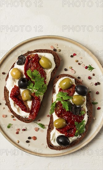 Breakfast, sandwiches with dried tomatoes, olives, and cheese cream, top view