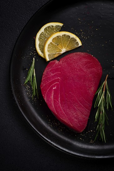 Fresh red tuna fillet, for steak, raw, top view, on a black plate, no people