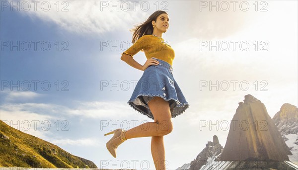 Woman walking in the mountains in sunny weather wearing a blue denim skirt and a yellow top, AI generated, AI generated