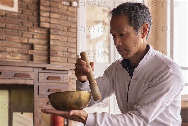 A young Asian adult, deeply absorbed in the practice of meditation, sits serenely amidst an atmosphere of tranquillity and harmony, enveloped by the rich tapestry of the Tibetan Buddhist tradition