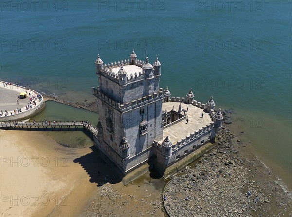 A historic tower by the sea, standing on a rocky sandy beach, with blue sky above, aerial view, Torre de Belém, World Heritage Site, Belem, Bethlehem, Lisbon, Lisboa, River Tagus, Portugal, Europe