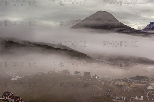 Inuit settlement, houses in the fog in front of steep mountains, Tasiilaq, East Greenland, Greenland, North America