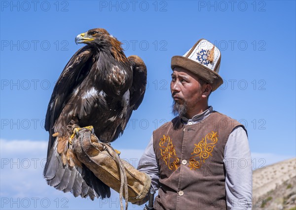 Traditional Kyrgyz eagle hunter with eagle in the mountains, near Kysyl-Suu, Kyrgyzstan, Asia