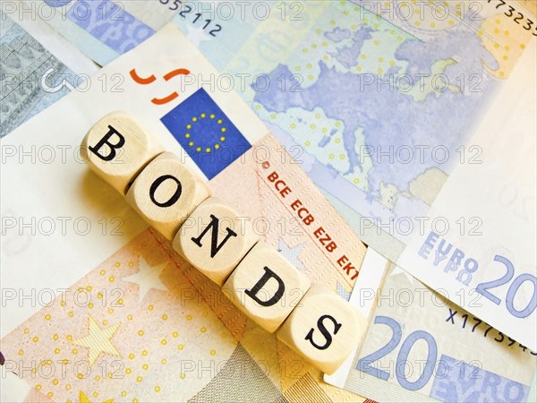 Wooden cube with the inscription 'BONDS' on a background of euro banknotes, outline of the European continent, Europe on one of the banknotes, EU flag, eurobonds, letter cube, symbolic image financial crisis, debt crisis, bailout, debt cut, finance, stability, monetary union, ESM, EFSF, debt, rescue fund