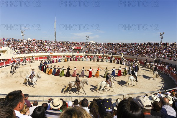 Women dance in traditional costumes and men ride horses in the arena of Les Saintes Maries de la Mer, Parc Naturel Regional de Camargue, Bouches du Rhone, Provence, France, Europe