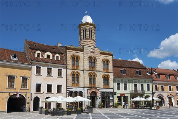 Historic architecture under a clear blue sky, cafés with parasols on the market square, Church of the Assumption of the Virgin Mary and town houses on the market square Piata Sfatului, Old Town, Brasov, Transylvania, Romania, Europe