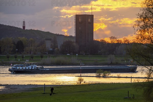 Cargo ship on the Rhine near Duisburg-Beeckerwerth, Rheinpreussen spoil tip in Mörs, spoil tip sign Das Geleucht, winding tower of the former Rheinpreußen Schacht VIII colliery, Duisburg, North Rhine-Westphalia, Germany, Europe