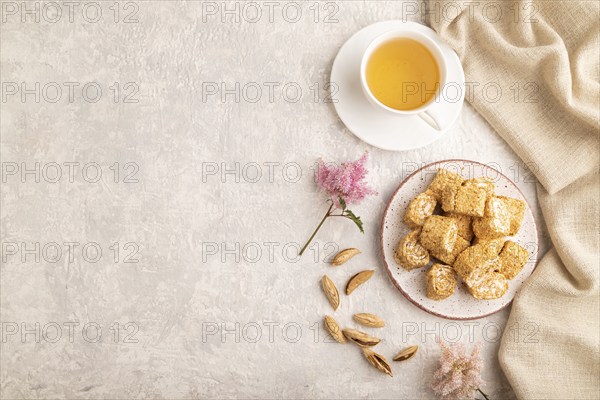 Traditional turkish delight (rahat lokum) with cup of green tea on a gray concrete background and linen textile. top view, flat lay, copy space