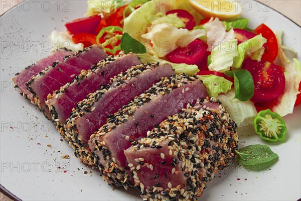 Fillet of red tuna meat, fried in sesame seeds, homemade, close-up, no people, on a wooden background