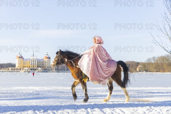 This year, the most popular fairytale film of all time is celebrating a special anniversary. At Moritzburg Castle, one of the film's locations, the exhibition on the cult film Three Hazelnuts for Cinderella is opening for the twelfth time - with an anniversary-worthy supporting programme and special exhibition. Model Tamara Kretschmer once again slipped into the coveted role of the legendary Cinderella with the ball gown. Here she rides the legendary film horse Catano, Moritzburg, Saxony, Germany, Europe