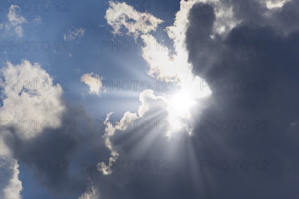 Rain clouds with sun shining through, rays of sunshine, blue sky