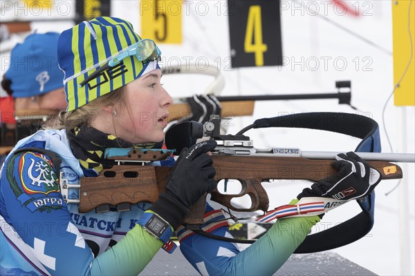 Russian sportswoman biathlete Legostaeva Anastasia rifle shooting in prone position. Biathlete in shooting range. Regional Junior biathlon competitions East of Cup. Kamchatka, Russia, April 12, 2019, Europe