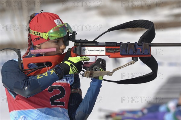 Sportswoman biathlete aiming, rifle shooting, reloads standing position. Biathlete Polina Yegorova Kazakhstan in shooting range. Junior biathlon competitions East Cup. Kamchatka, Russia, Apr 14, 2019, Europe