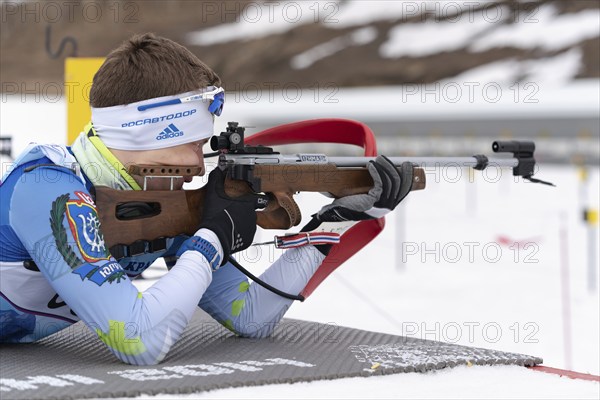 Sportsman biathlete Morilov Mikhail Khanty-Mansiysk aiming rifle shooting prone position. Biathlete in shooting range. Regional youth biathlon competitions East Cup. Kamchatka, Russia, April 12, 2019, Europe