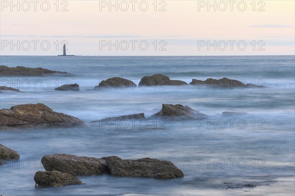 The lighthouse of the barges on the horizon seen from the beach of Sauveterre. Les Sables d'Olonne, Vendee, Pays de la Loire, France, Europe