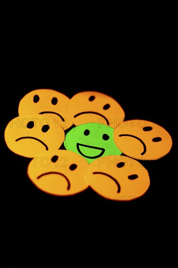 Paper cutouts of sad smileys surrounding a happy smiley. concept of positivism, social problems, discrimination, psychology, homophobia.... Vertical view