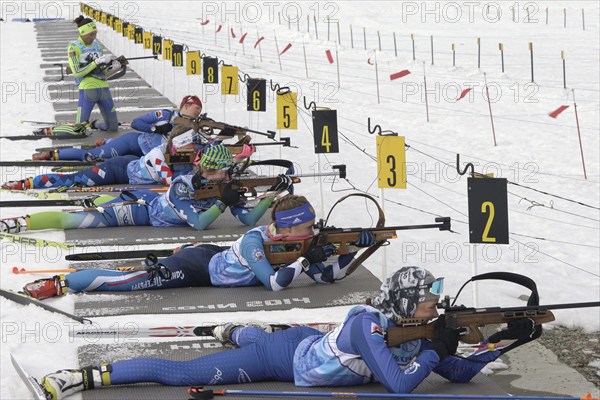 Group sportswoman biathlete aiming, rifle shooting and reloading rifle in prone position. Biathletes shooting range during Junior biathlon competitions East of Cup. Kamchatka, Russia, April 13, 2019, Europe