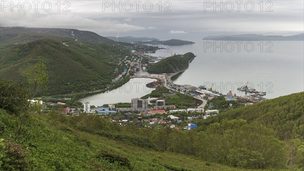 Summer cityscape of Kamchatka Peninsula: scenery top view of seaport, center of Petropavlovsk-Kamchatsky City, mountains along shores of Avacha Bay (Avachinskaya Bay), Pacific Ocean. Russian Far East